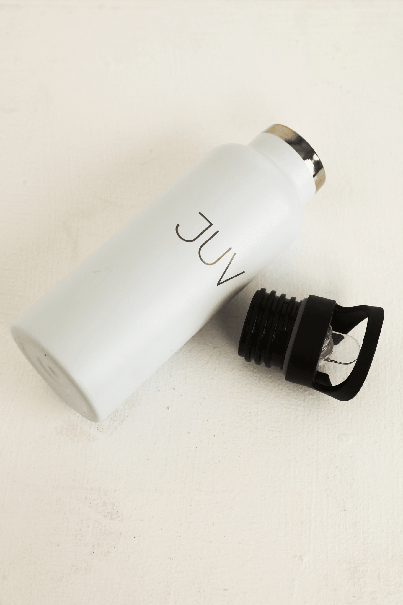 JUV pure thermal bottle with sipper in white with the cap on the side, side view.